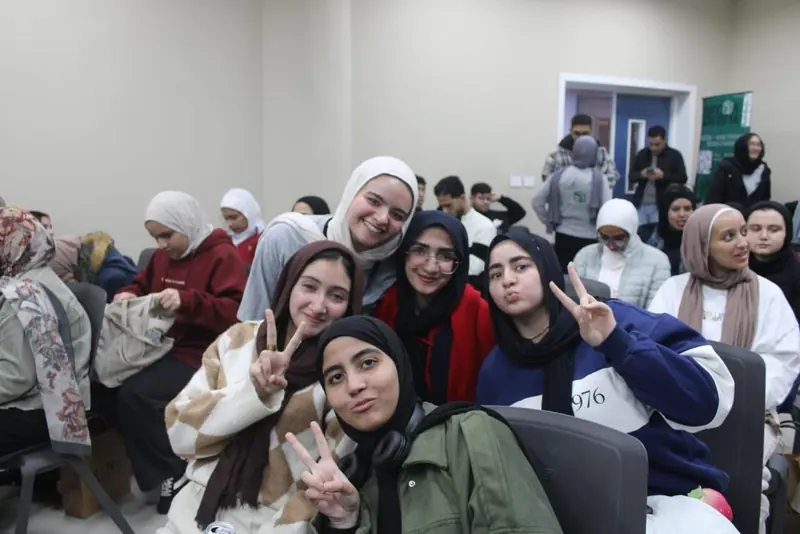 Members in the audience smile and make peace signs at the camera