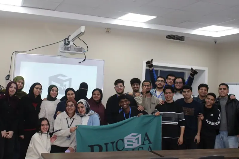 Participants cheer with their arms raised behind the BUCSA EMSA flag